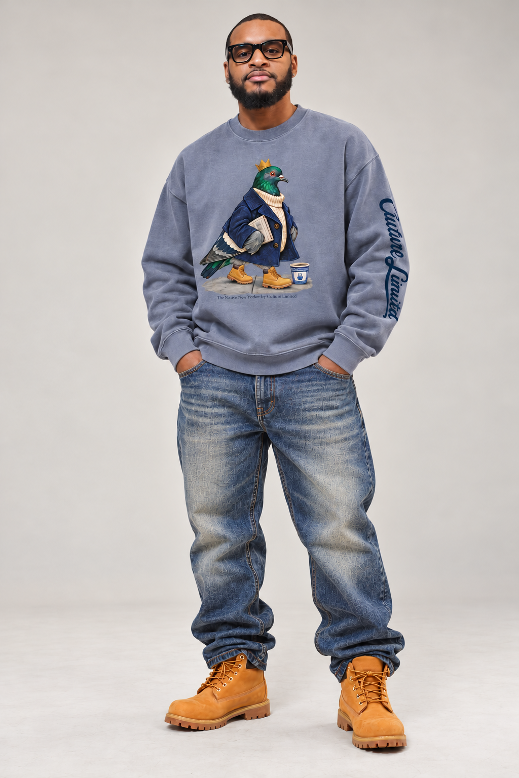 Model wearing the blue-grey Native New Yorker pigeon crewneck with Culture Limited sleeve lettering, relaxed jeans and wheat boots.